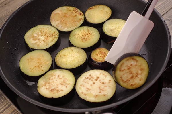 Баклажаны обжарить с двух сторон на хорошо разогретой сковороде с растительным маслом до золотистого цвета.