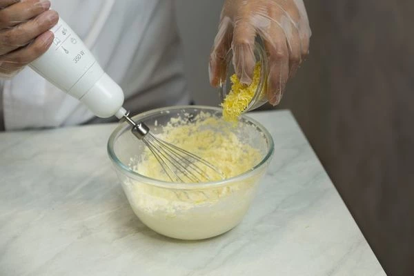 Взбейте блендером размягченное сливочное масло с сахаром до бела, добавьте цедру лимона, ванильный сахар.