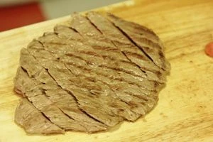 Обжаренные овощи выложить на тарелку. Стейк нарезать тонкими пластиками под углом. Выложить на овощи и полить соусом.