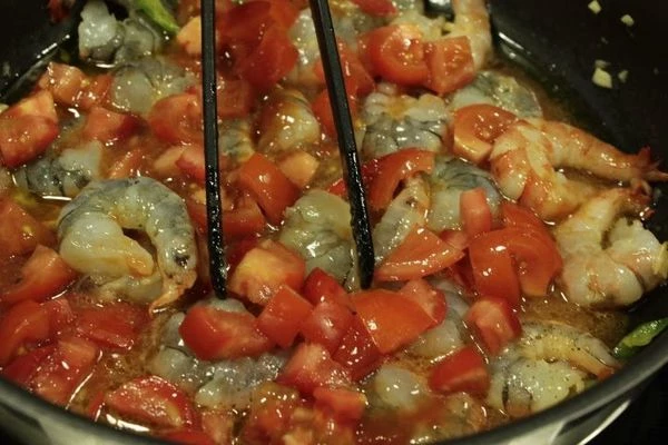 На разогретой с оливковым маслом сковороде обжарить чеснок, добавить креветки, помидоры. Жарить 5 минут.