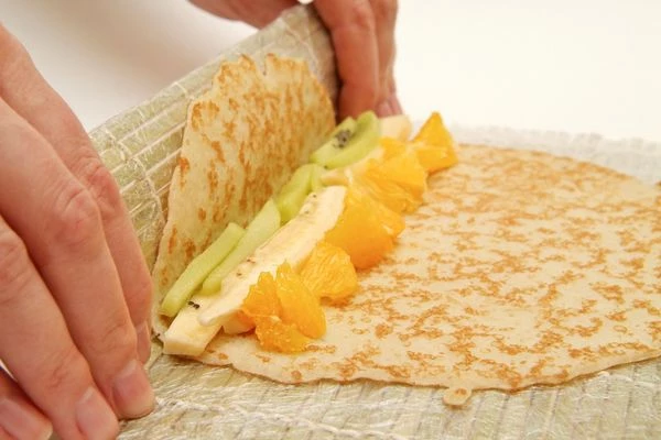  Свернуть блинчик с начинкой рулетом при помощи бамбукового коврика

 