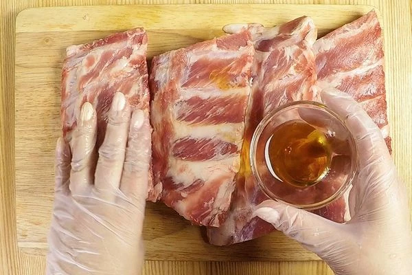 Ребра разморозить естественным способом на нижней полке холодильника, разрезать на порции, смазать жидким дымом. 