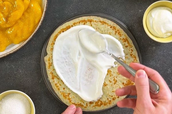 Блинчик выложить на форму для запекания. Смазать его сметаной.