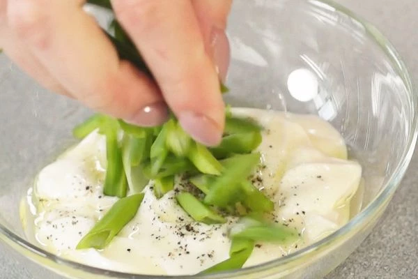Для заправки смешать йогурт, нарезанный зелёный лук, оливковое масло и специи. 