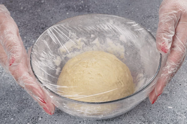 Скатать тесто в шар, накрыть пищевой пленкой и поставить в теплое место для подъема на час.