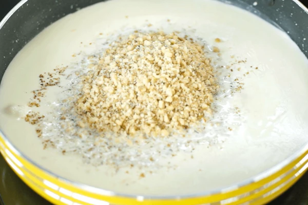 Сливки влить в сковороду, довести до кипения, добавить чеснок, молотые орехи, соль, перемешать, довести до кипения, снизить нагрев. Слегка выпарить соус.
