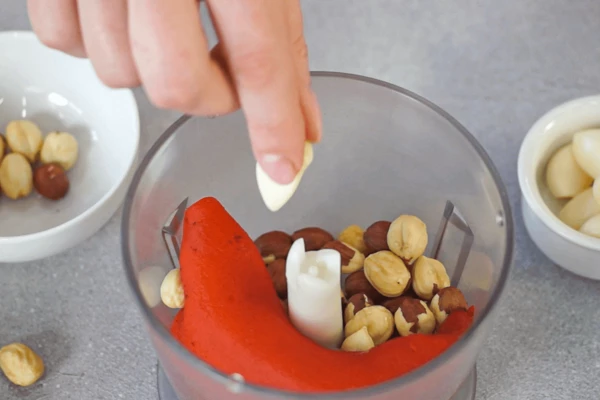 Для соуса в чаше блендера соединить печеный перец, фундук, оливковое масло (50 гр.), зубчик чеснока и соль. Измельчить до однородной консистенции.
