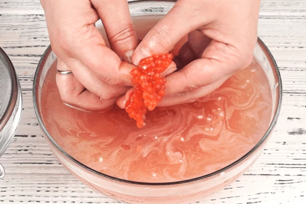 Икорные ястыки сначала промываем (раскрываем) в холодном рассоле, аккуратно отделяя икринки руками. Затем сливаем рассол через сито. 