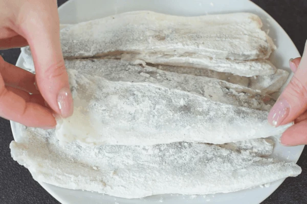 Филе разморозить на нижней полке холодильника, обвалять в муке со специями.