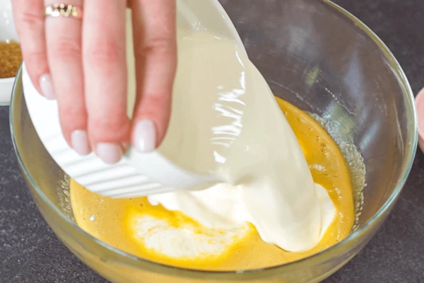 В емкость к желткам налить сливки, добавить ванилин, перемешать.