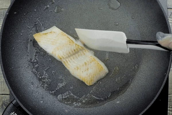 Рыбу разморозить естественным способом на нижней полке холодильника. Нарезать на порционные куски ~150 г. Обсушить бумажным полотенцем. Сковороду разогреть, рыбные стейки обжарить на небольшом количестве растительного масла до золотистого цвета (примерно по 1 минуте с каждой стороны). В конце посолить, поперчить, снять с огня.