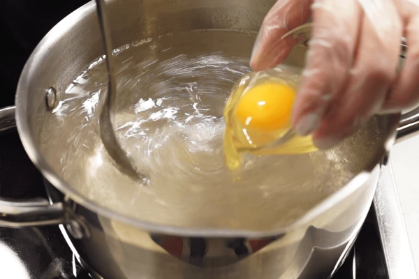 Чтобы удобнее было выливать яйцо, можно разбить его в небольшую чашку. Затем ложкой в центре раскрутить воду в виде воронки и аккуратно влить яйцо. Варить 3-4 минуты