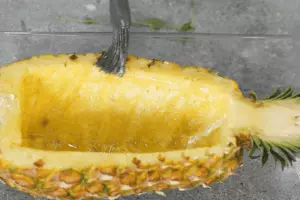 Смазать внутреннюю часть половинки ананаса маслом, положить срезом вверх на противень. Запекать в разогретой до 180°С духовке, пока поверхность слегка не карамелизуется, примерно 15 минут. 
