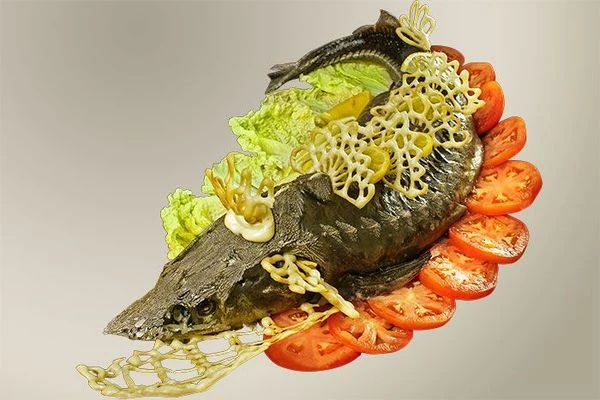 Готовую рыбу переложить на украшенную овощами тарелку. Оформить  узорами из заварного теста и лимоном.