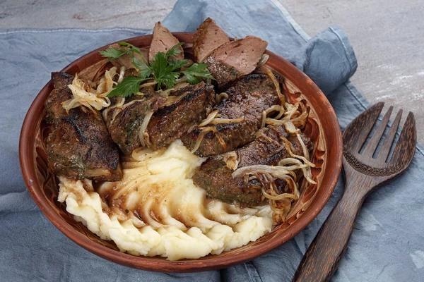 Горячее пюре выложить рядом с печенью, украсить нарезанной зеленью.