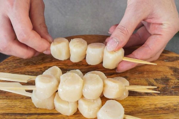 Гребешок разморозить на нижней полке холодильника. Удалить ножку крепления. Нанизать мясо гребешка на шпажки. 
