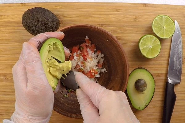 Авокадо разрезать на половинки, удалить косточку и, разминая вилкой, выбрать всю мякоть. 