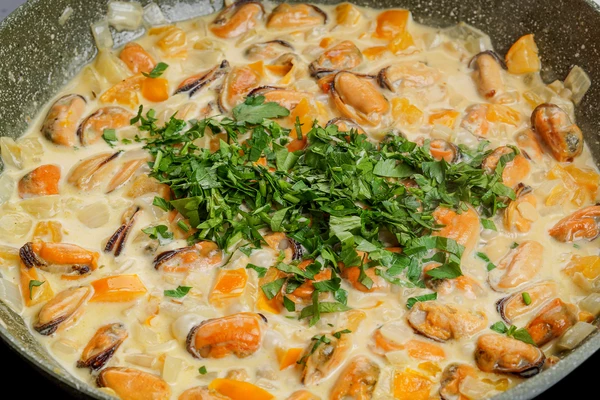 Влить сливки, прогреть до закипания. Добавить мелконарезанную зелень.