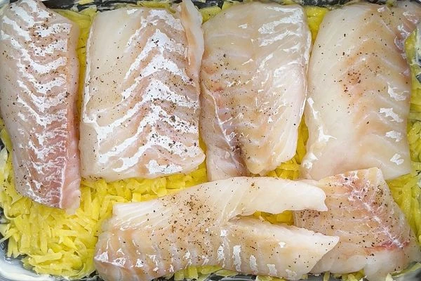 Поверх картофеля положить кусочки трески.