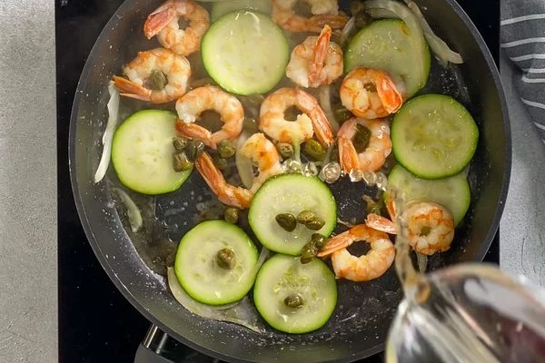 Добавить каперсы и влить белое вино и посолить.