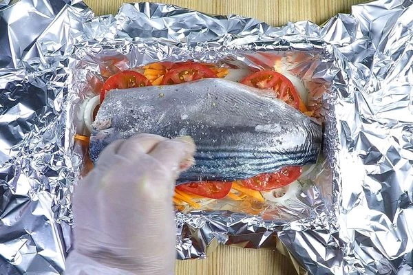 Затем добавить морковь, кружочки помидора. Посолить, поперчить по вкусу. Сверху выложить филе рыбы, кожей вверх. 