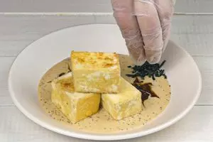 На тарелку налить соус, сверху уложить кусочки хрустящего тофу, украсить по желанию водорослями.