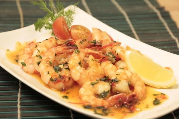 В центр тарелки выложить подготовленный рис горкой, рядом жареные креветки, полить оставшимся соусом. Украсить лимоном, помидорами черри.