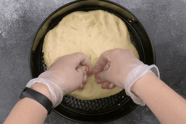 На дно смазанной формы выложить тесто, формируя бортики около 2 см.