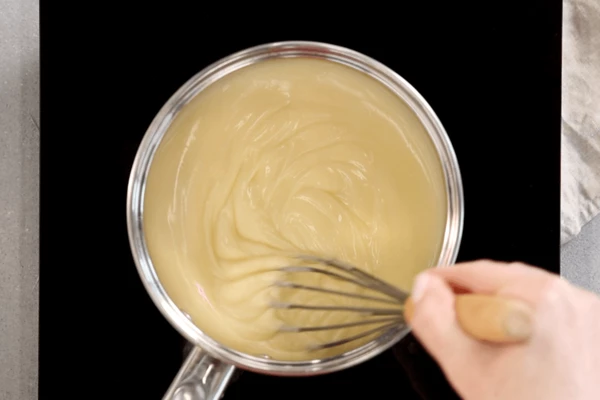 Варить до загустения и первого булька, постоянно помешивая венчиком. Снять с огня, переложить в миску под пленку «в контакт» и полностью остудить. Как вариант можно отправить горячий крем в стационарный миксер с насадкой весло, включить среднюю скорость и так охладить. 
