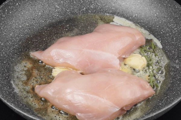 На разогретую сковороду добавить смесь сливочного и растительного масла, раздавленные зубчики чеснока, веточки розмарина. Обжарить грудку, с двух сторон до румяной корочки. 