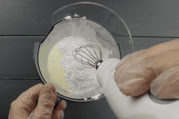 В глубокой чаше взбить сливки с сахарной пудрой до плотной массы