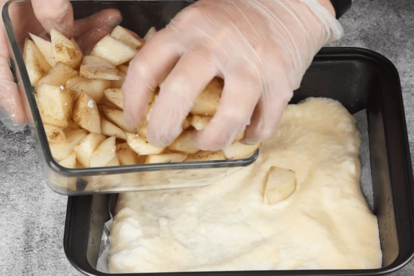 На дно противня застелить пергамент, немного смазать растительным маслом. Выложить часть теста, затем грушу.