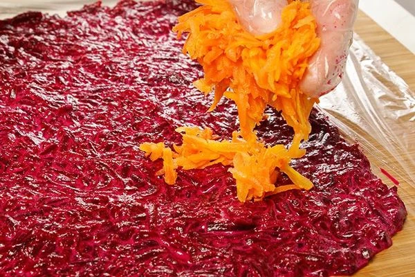 На доску расстелить пищевую пленку. На пленку выложить свекольную массу в виде прямоугольника. Длина сторон зависит от размера рулета.