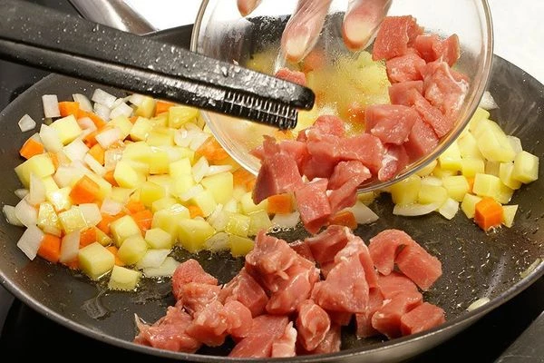 На разогретой с растительным маслом сковороде обжарить сначала лук и морковь до золотистого цвета, затем добавить картофель, жарьте еще 2-3 минуты. Отодвинуть овощи в сторону и обжарить на второй половине сковороды мясо.