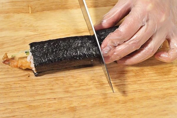  Нож смочить в воде и разрезать ролл пополам.