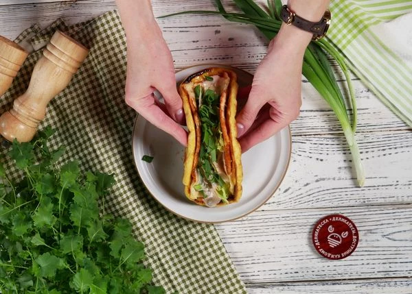 Посыпать зеленым луком и сложить питу пополам.