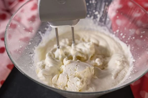 Затем добавить творожный сыр, тщательно перемешать. Крем переложить в кондитерский мешок.
