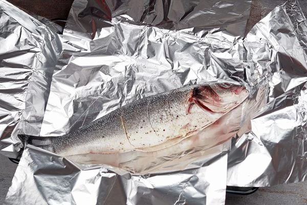 Подготовленную рыбу выложить на фольгу и завернуть в форме лодочки.