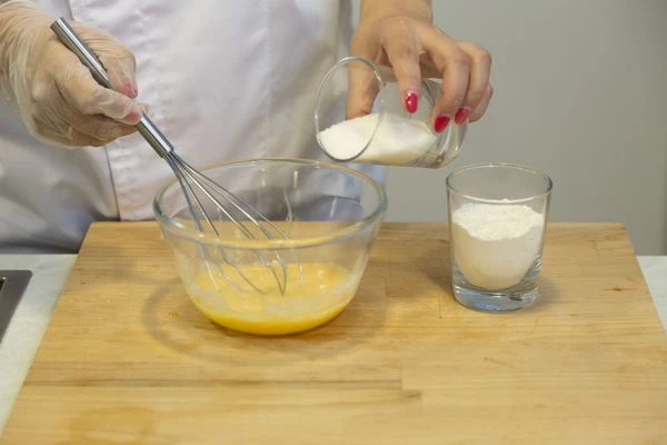 В глубокой чашке венчиком взбить яйца с сахаром до однородной консистенции. К яичной смеси добавить муку и хорошо перемешать.