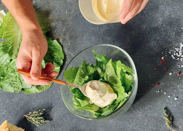 Смешать листья салата с соусом.