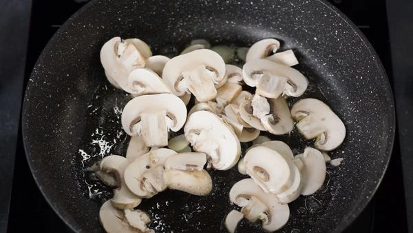 В сковороду добавить оливковое и сливочное масло, разогреть, обжарить чеснок, затем ввести нарезанные шампиньоны, обжарить. 

