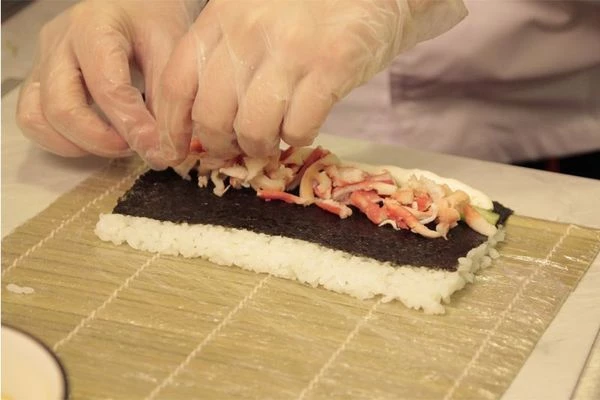 Пока рис варится, сделаем соус. В кастрюлю влейте рисовый уксус, добавьте кусочек комбу, сахар и соль. Варите до тех пор пока сахар и соль не растворятся. Комбу можно удалить.