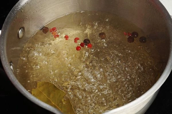 Добавить в воду соль, сахар (по желанию, если любите сладковатые огурчики), перец горошком, лавровый лист. Проварить 7-8 минут. Снять с огня, добавить уксус.