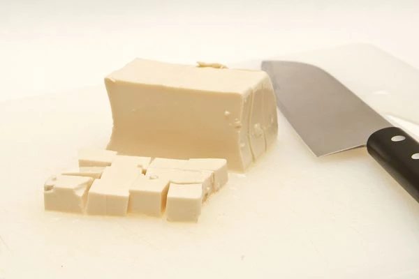 Пока готовится бульон, кубиками нарежьте соевый творог тофу и разложите по чашкам.