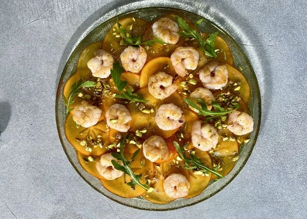 Посыпать рубленными фисташками. Оформить рукколой. Оставить на 10 минут для того, чтобы хурма подмариновалась. Приятного аппетита!