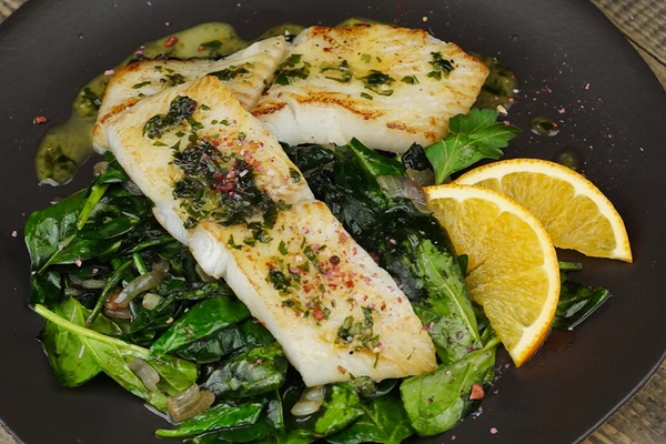 На тарелку выложить горкой «подушку» из шпината, сверху уложить филе жареного палтуса, полить апельсиновым соком.