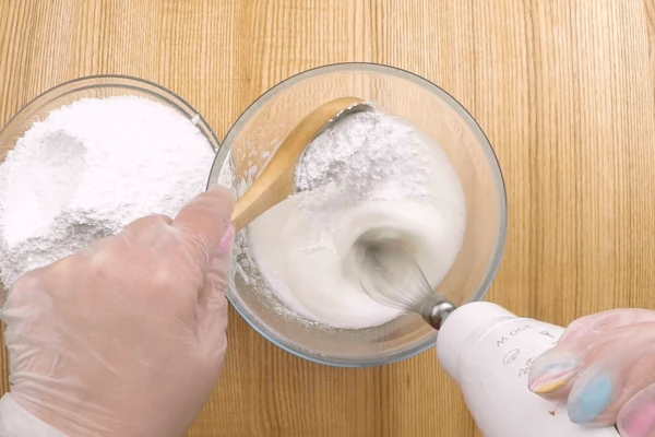 Затем порциями подмешиваем сахарную пудру, продолжая взбивать. Когда миксером уже пробить будет трудно, можно продолжить венчиком. Это сахарная основа, которую мы будем дальше использовать. 