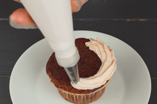 С помощью кондитерского мешка украсить кексы кремом