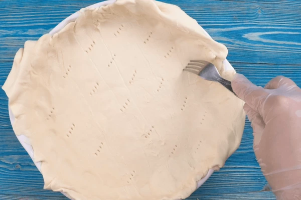  Форму для выпекания смазать немного растительным маслом, выложить тесто, по всему периметру дна сделать проколы вилкой.