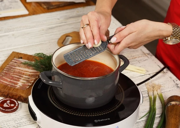 Натереть зубчик чеснока, выключить нагрев. Накрыть крышкой и дать постоять 5-7 минут. 